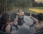 Pareja-en-tinaja-caliente-con-champagne-tabla-y-atardecer-dorado