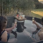 Pareja-en-tinaja-caliente-con-champagne-tabla-y-atardecer-dorado